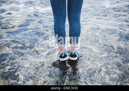 Young Woman Wearing Water Shoes Standing on Rock, Canon Beach, Oregon, USA Stock Photo