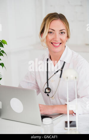 Portrait of young woman doctor with stethoscope in white coat at computer Stock Photo