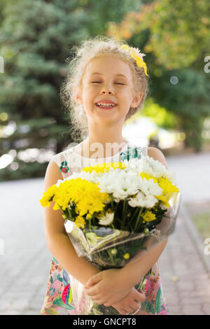 Smiling happy little girl with bouquet of flowers, summer outdoor Stock Photo