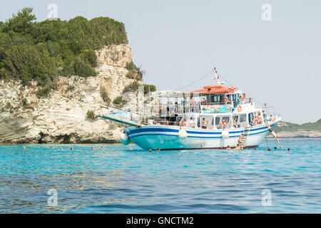 Tourists on a day trip from nearby Corfu swimming in the sea from a cruise boat moored off the tiny Ionian island of AntiPaxos Stock Photo