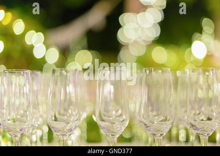 Row of wine glasses in green background painted with beautiful bokeh. Stock Photo