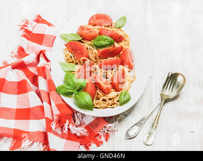 Spaghetti with roasted tomatoes and fresh basil over white background Stock Photo