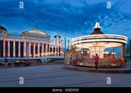 Skopje, Republic of Macedonia - May 4, 2015 : Spinning carousel in front of Archaeological Museum at twilight Stock Photo