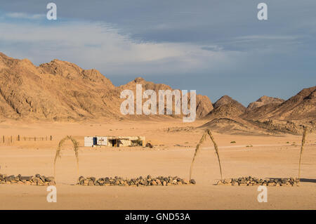 Bedouin village in the desert in Egypt. Plane terrain and high mountains. Cloudy early evening sky. Stock Photo