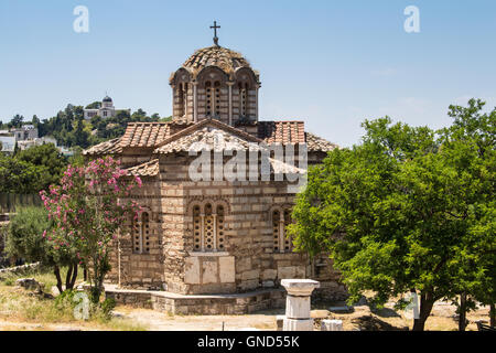 Old orthodox basilica in the city center of Athens. Park with olive and oleander trees. Hill in the background. Blue sky. Stock Photo