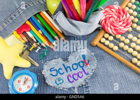 School is cool sign with creative learning objects on blue jeans Stock Photo