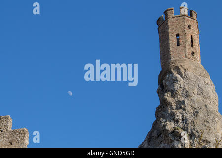 Part of ruins of castle Devin in Slovakia.  Maiden tower, built on the edge of a high rock. Bright blue sky with moon. Stock Photo