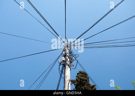 Tangled power cables connected to power supply on wooden pole Stock Photo