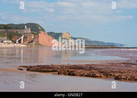 The view along the beach looking towards Jacobs ladder at Sidmouth at low tide  with the hills of Devons jurassic coast behind Stock Photo