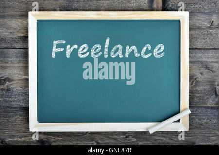 Freelance text on school board and chalk on wooden table Stock Photo