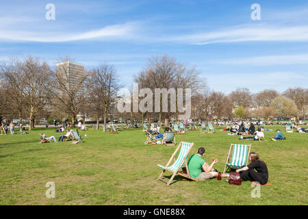 People sitting in the April sunshine at Hyde Park, London, England, UK Stock Photo