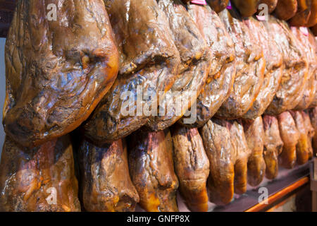 Lines of shiny cured iberico ham hanging legs. Spain Stock Photo