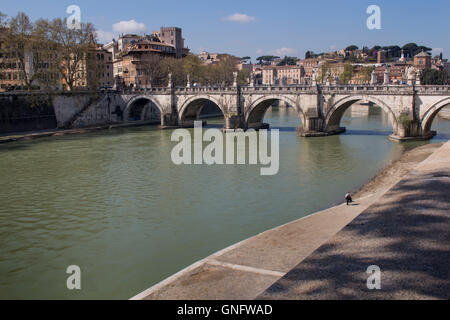 Part of Rome close to the Castle. Old bridge over the Tiber River. Buildings of the old city in the background. Blue sky with fe Stock Photo