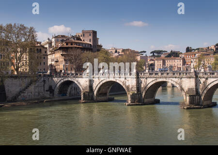 Part of Rome close to the Castle. Old bridge over the Tiber River. Buildings of the old city in the background. Blue sky with fe Stock Photo