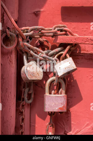 3 old padlocks on the old gate, which is painted red. The padlocks are hanging on a massive chain. — Photo by YassminPhoto Stock Photo