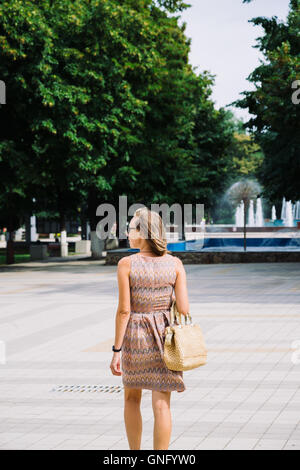 Young brunette woman walking in park against of fountain Stock Photo