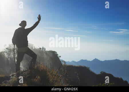 Silhouette of a man standing on mountain waving, Mount Batur, Bali, Indonesia Stock Photo