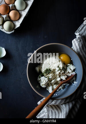Ricotta soft cheese in a mixing bowl with eggs and herbs. Stock Photo