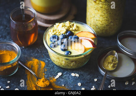Healthy Golden milk overnight oats for breakfast with fresh fruits {gluten-free) Stock Photo