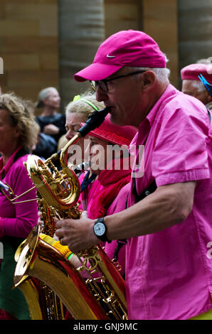 Man in pink playing saxophone with a marching horns band taking part in the Cavalcade, part of the Edinburgh Jazz Festival. Stock Photo