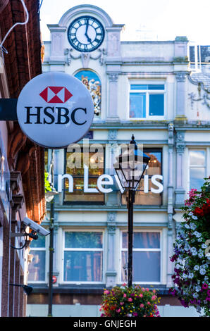 An HSBC sign hangs from the side of a bank in Reading, Berkshire and John Lewis can be seen in the distance. Stock Photo