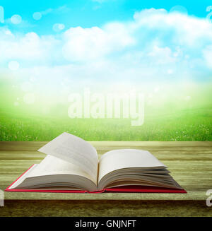 Open book on table in front of grass and sky Stock Photo