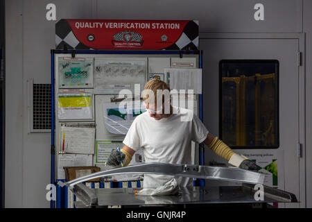 Sterling Heights, Michigan - A worker checks the quality of auto parts emerging from a stamping press. Stock Photo