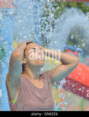 Beautiful woman enjoying under a water jet with thousands of drops in the background Stock Photo