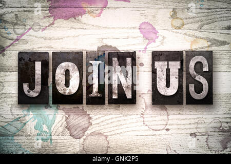 The words "JOIN US" written in vintage, dirty metal letterpress type on a whitewashed wooden background with ink and paint stain Stock Photo