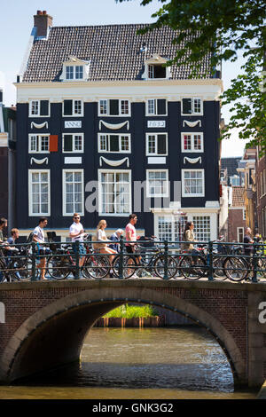 Canalside cyclists house and bridge at Herengracht / Singel in Jordaan District of Amsterdam, Holland Stock Photo