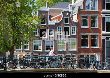 Canalside cyclists house and bridge at Herengracht / Singel in Jordaan District of Amsterdam, Holland Stock Photo