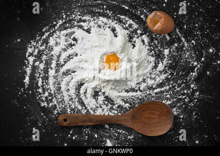 Spiral Galaxy on the Kitchen spelled by Wheat flour on black chalkboard with wooden spoon and broken chicken egg Stock Photo