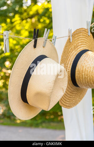 Image of straw hats hanging on a clothes line outdoors. Stock Photo