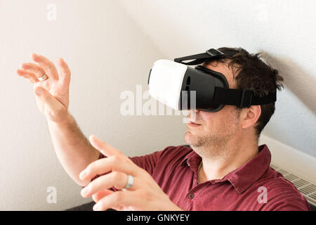 Man resting on sofa wearing VR headset glasses Stock Photo