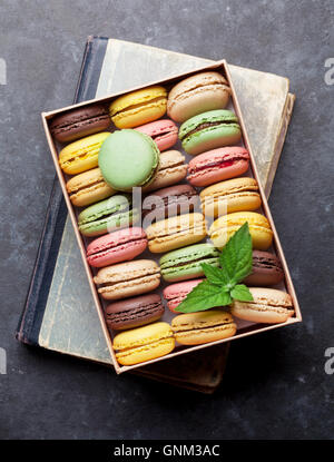 Colorful macaroons in a gift box on stone table. Sweet macarons. Top view Stock Photo