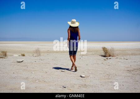 Beautiful woman walking alone on the beach at the Salton Sea, California. With clear blue sky. Stock Photo