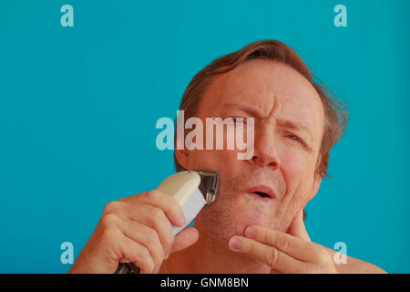 a man  shaves  his beard with eletric razor Stock Photo