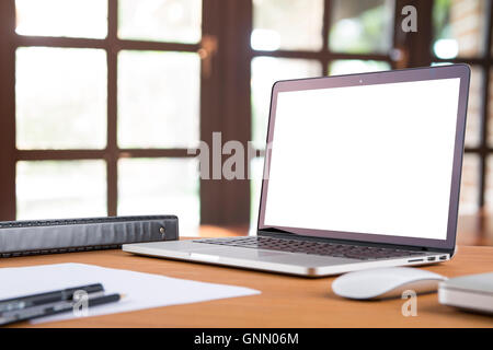 Morning time with warm light. Blank laptop screens on working wooden desk with pen, pencil, document, and text book. Stock Photo