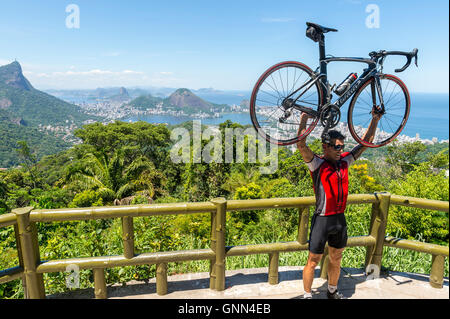 RIO DE JANEIRO - FEBRUARY 24, 2015: Cyclist poses with his bicycle aloft after making the steep ascent to the Vista Chinesa. Stock Photo