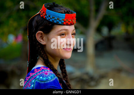 A beautiful Kalasha girl smiles as she passes a forest in Kalash Valley, Chitral, Pakistan. Stock Photo