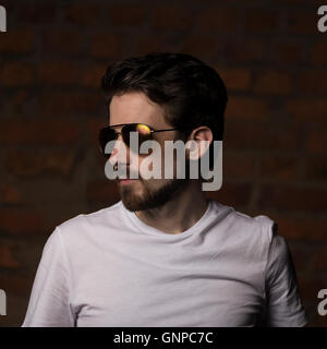 Male model with groomed beard wearing white tee and aviators reflecting red orange yellow sunset light Stock Photo