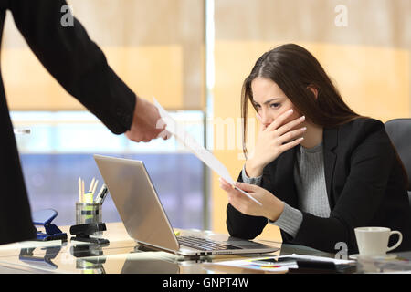 Worried businesswoman receiving a notification from a colleague in her workplace at office Stock Photo