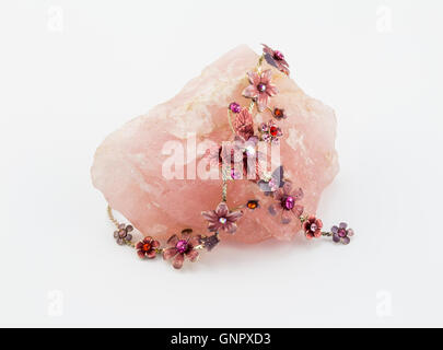 Rose quartz crystal rock and pink flower costume jewellery necklace isolated on white Stock Photo