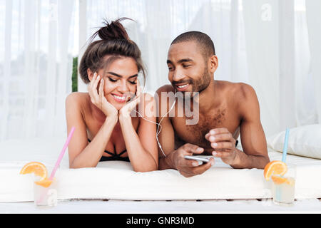 Young happy couple in love listening to music with earphones at the beach Stock Photo