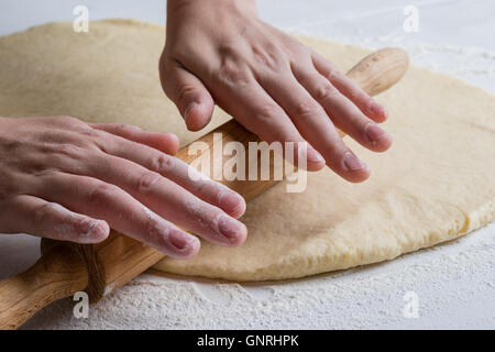 womans hands spreading dough with rolling pin Stock Photo