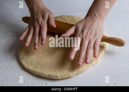 womans hands spreading dough with rolling pin Stock Photo