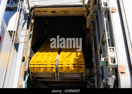 Yellow plastic bristles on a conveyor belt used as large scale oil recovery equipment on ship. The bristles separate the crude f Stock Photo
