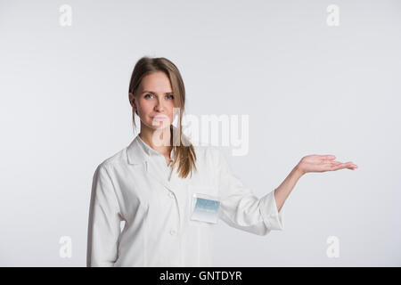 Portrait of beautiful nurse looking at camera and gesturing. Beautiful clinic assistant show to copy space Stock Photo