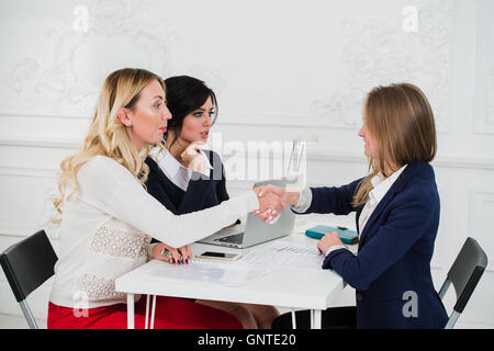 Two Businesswomen Shaking Hands In Modern Office Stock Photo