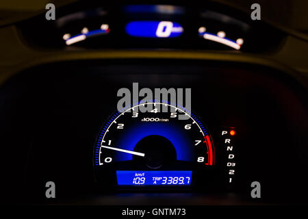 Car dashboard displaying illuminated speedometer and tachometer in HDR. Stock Photo